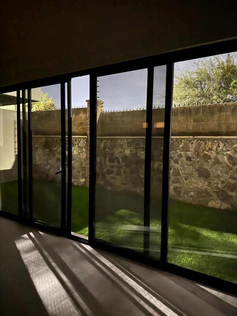 Jardín con pasto sintético y muro de piedra